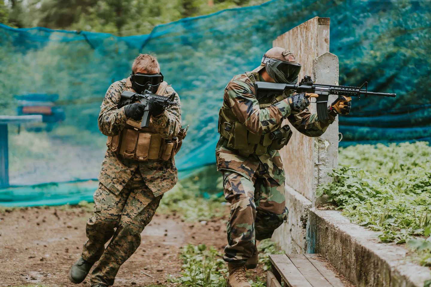 Divi airsofta spēlētāji ekipējumā Mežaparka āra laukumā