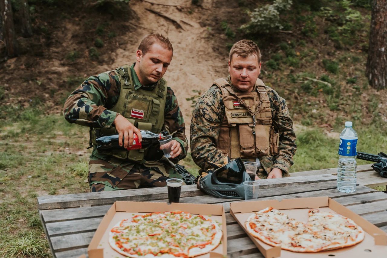 draugi atpūšas pēc airsoft spēles mežaparkā