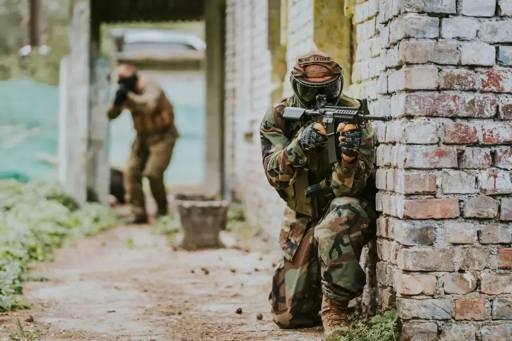 Players in full gear during an airsoft game in Riga at GUNSnLASERS park, participating in a tactical team scenario outdoors