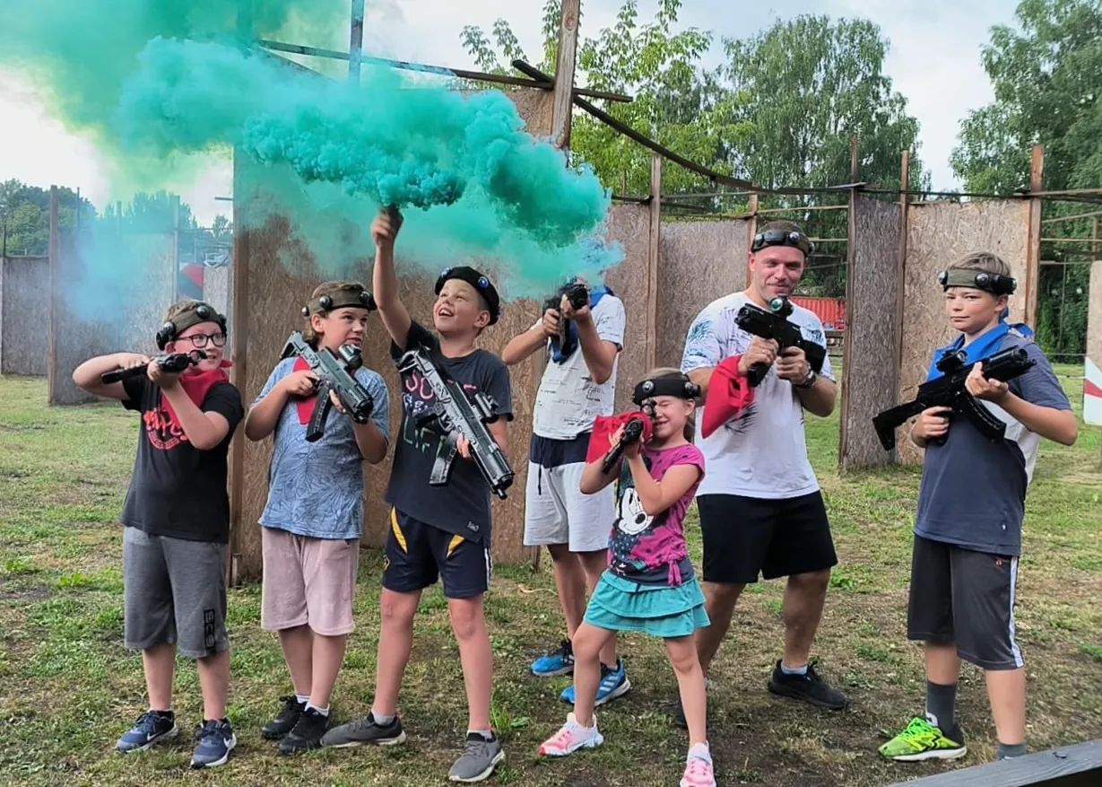 Bērnu grupa ar lāzertaga ieročiem un krāsainiem dūmiem Šampēterī