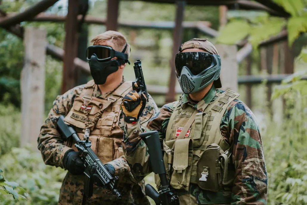 Divi airsofta spēlētāji maskās un pilnā ekipējumā