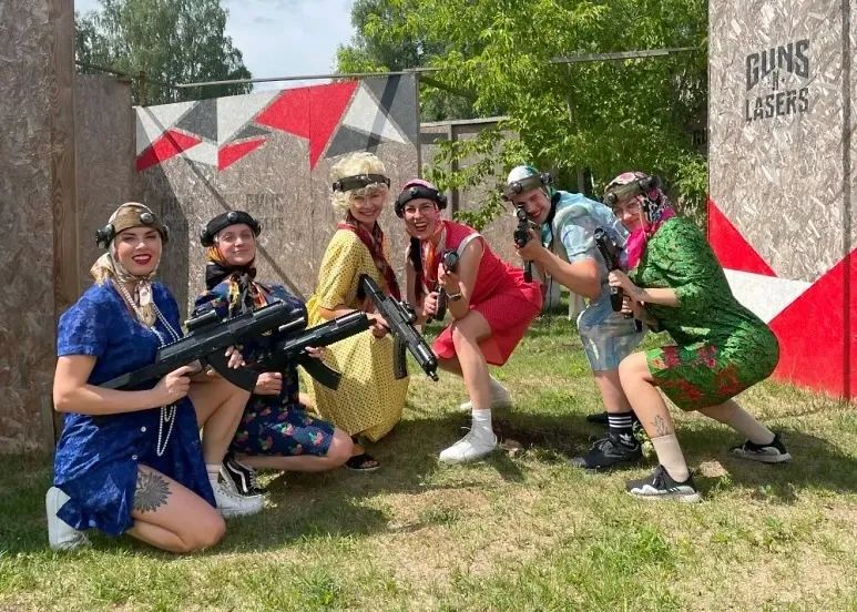 Draugu grupa krāsainos tērpos ar lāzertaga ieročiem