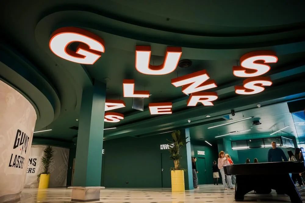 Izgaismota GUNSnLASERS izkārtne virs ieejas Galerija Centrs