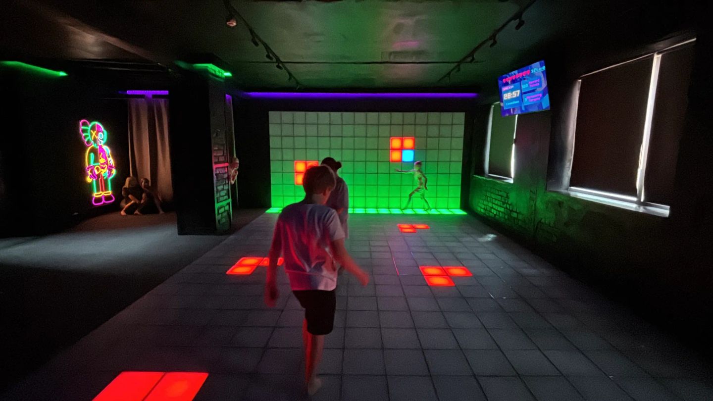 Bērns spēlē GUNSnLASERS pikseļu istabā