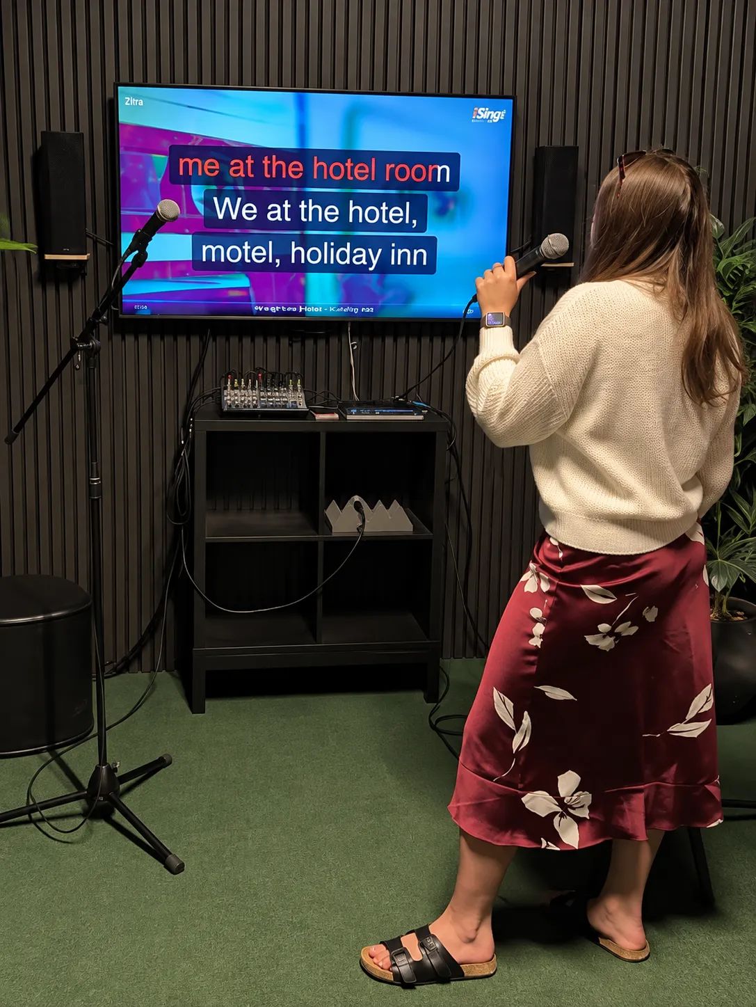 Meitene dzied Pitbull dziesmu karaoke istabā.